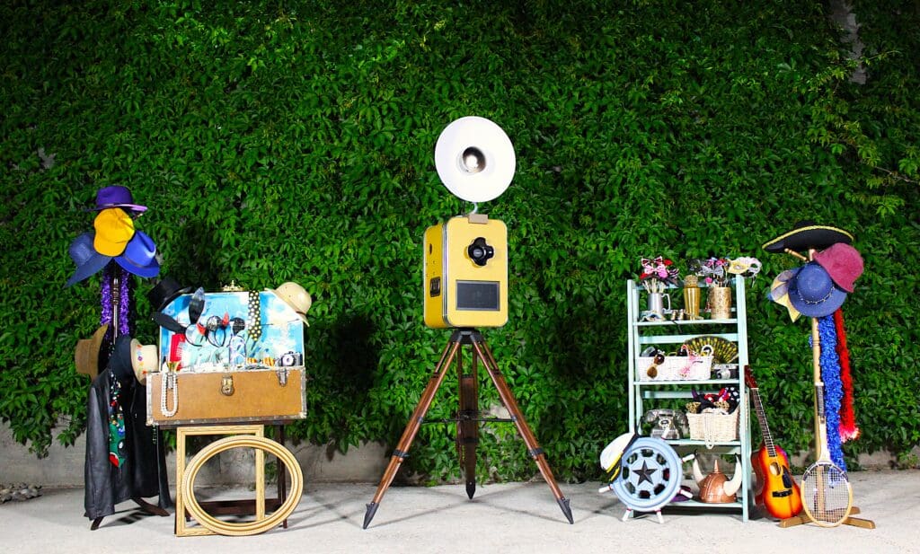 Classic Vintage style open-air photo booth at a wedding in Carmel-by-the-Sea, California. Floral Ivy backdrop with retro wedding photo booth props. Awesome Sauce Photo Booth provided by DJ Enterprises Mobile Disc Jockey. Awesomesauce Photo Booth Package. Icebreaker Photo Booth. Wedding Photo Booth rentals in Monterey, California. #WeddingPhotoBooth #MontereyWeddingDJ #AwesomesaucePhotoBooth #WeddingPhotoBoothProps
