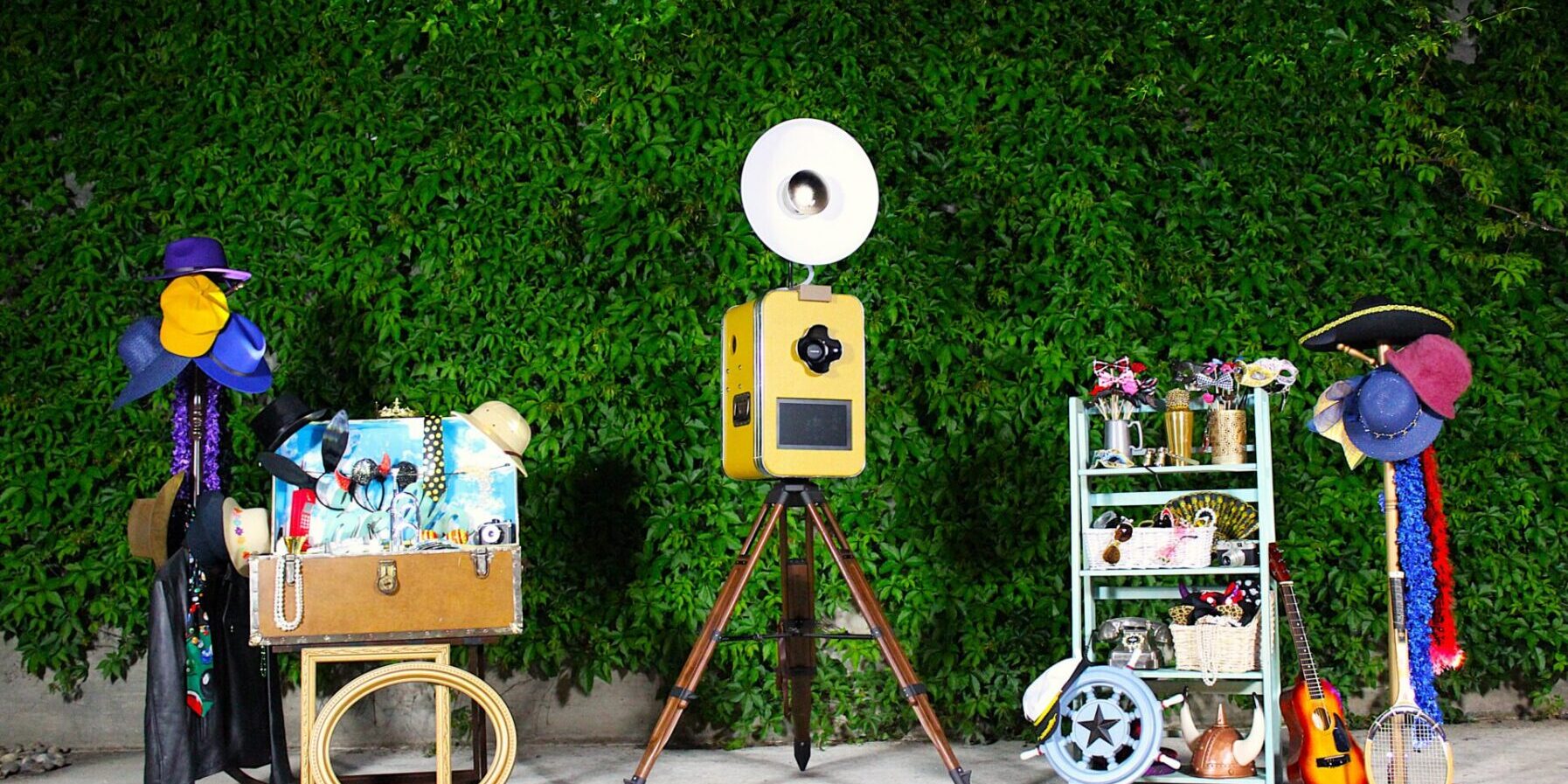 Classic Vintage style open-air photo booth at a wedding in Carmel-by-the-Sea, California. Floral Ivy backdrop with retro wedding photo booth props. Awesome Sauce Photo Booth provided by DJ Enterprises Mobile Disc Jockey. Awesomesauce Photo Booth Package. Icebreaker Photo Booth. Wedding Photo Booth rentals in Monterey, California. #WeddingPhotoBooth #MontereyWeddingDJ #AwesomesaucePhotoBooth #WeddingPhotoBoothProps